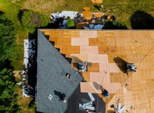 Homeowner photographing missing shingles and ceiling water stains after a storm.