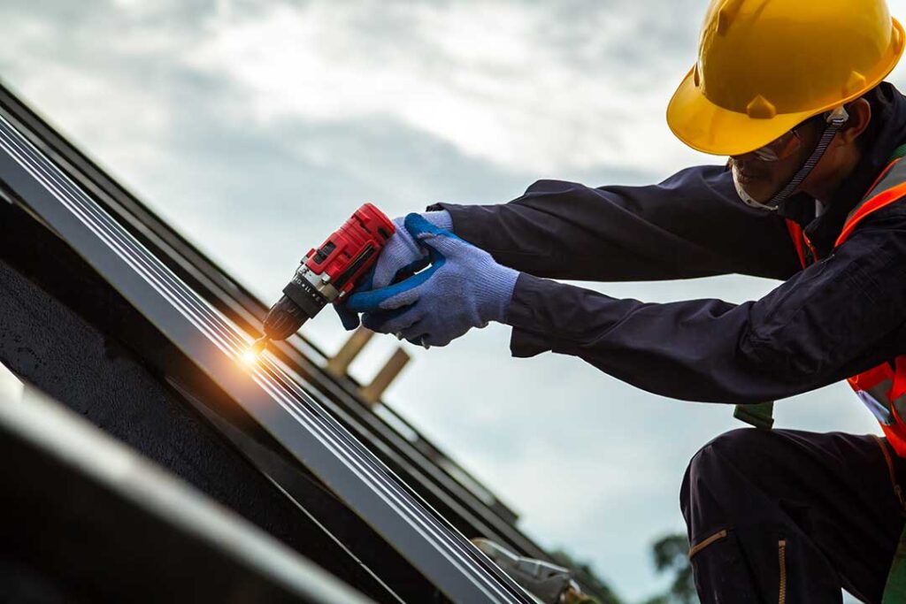 A homeowner examines evenly distributed attic insulation beside roof ventilation baffles and sealed ceiling penetrations.