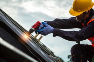 A homeowner examines evenly distributed attic insulation beside roof ventilation baffles and sealed ceiling penetrations.